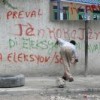 Graffiti artist. Wall says in part: "Down with Preval", "Down with selection election", "Aristide Lives". Credit: Judith Scherr/IPS