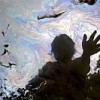 Cancer victim Maria Garofalo reflected in the stream behind her home in the Ecuadorean Amazon. From the film "Crude". Credit: Juan Diego Pérez