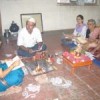 The priest, Manisha Shete (in blue saree) explains the puja to the yajman (host), Vidyadhar Kulkarni. Credit: Daksha Warty/IPS