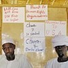 Two internally displaced persons at the Hamadiya camp in Zalingei, West Darfur, in front of posters calling for UN intervention. Credit: UN Photo/Fred Noy 
