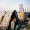 A young woman smiles from her tent-like hut in the shadow of the most luxurious hotel in Dhaka, Bangladesh. Credit: Shehzad Noorani/Still Pictures