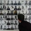 A tourist peers at photographs of people who died in Khmer Rouge custody. Credit: Robert Carmichael/IPS