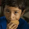 A child eats a World Food Programme nutritional biscuit. This year, WFP will help feed more than 100 million people. Credit: WFP/Shehzad Noorani